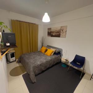 a bedroom with a bed and a tv and a chair at Cardia’s Guest House in Sacavém