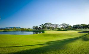 a lush green golf course with a lake in the middle at Vidanta Grand Luxxe 3 BR Loft 16 rounds of Golf tennis 2 Massages included in Nuevo Vallarta