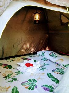 a bed in a tent with a flower on it at Bucana Beach Camp in El Nido