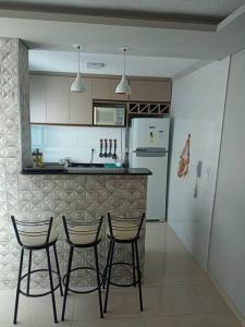 a kitchen with three bar stools and a refrigerator at Apartamento locação diária - residencial Belize in Botucatu