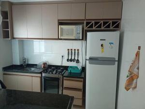 a small kitchen with a refrigerator and a microwave at Apartamento locação diária - residencial Belize in Botucatu