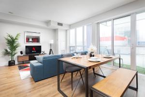 een woonkamer met een blauwe bank en een tafel bij 3 Beds w/ CN Tower View Right Beside Rogers Centre! in Toronto
