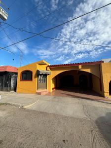a yellow house with a garage on a street at Depa a unos minutos de consulado! in Hermosillo