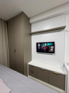 a bedroom with a flat screen tv on a wall at Studio cama King Size Westfit. in Mossoró