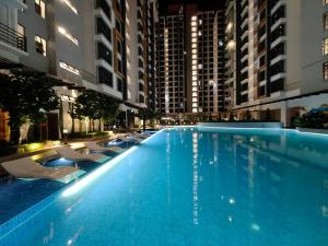 een groot zwembad met stoelen en gebouwen bij K Avenue Comfort Studio 3 Pax (5 mins to Airport) in Kota Kinabalu