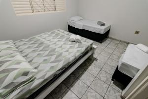 two twin beds in a room with a tiled floor at Suíte 01 Pousada Roosevelt in Uberlândia