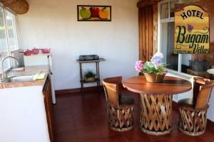 eine Küche mit einem Holztisch mit Stühlen und einem Waschbecken in der Unterkunft Hotel Bugamvillas Tapalpa in Tapalpa