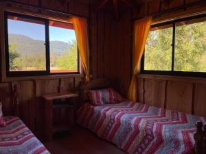 a bedroom with two beds and two windows at Valle Hermoso in Panguipulli