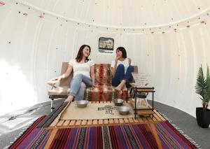 Due donne sedute su un divano in una tenda di Kuruma Asobi Adventure Field Appi - Camp - Vacation STAY 42063v a Hachimantai