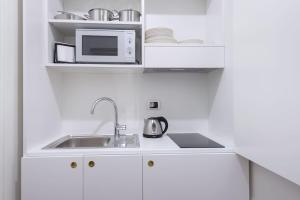 a white kitchen with a sink and a microwave at Discover the Pantheon from The Berardi Studio Flat in Rome