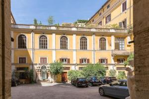 a large yellow building with cars parked in a parking lot at Discover the Pantheon from The Berardi Studio Flat in Rome