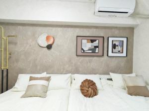 a bedroom with a white bed with pictures on the wall at G35新宿最中心 東新宿站5分-Shinjuku center 5 mins to Station, Max 4P 新宿 涉谷 表参道 池袋 上野 代代木 银座 原宿 in Tokyo