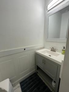 a white bathroom with a sink and a mirror at Point Breeze South Philly (2 bedrooms) in Philadelphia