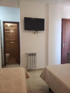 a room with two beds and a flat screen tv on the wall at ALTOS DE ALEM in Alta Gracia