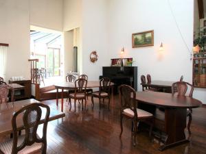 a room with tables and chairs and a piano at Kiyosatokogen Country Inn The Classic in Hokuto