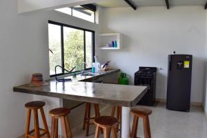 a kitchen with a large counter with stools and a refrigerator at Piedras del Sol Casa Campestre in Guaduas