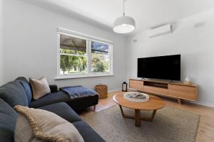 a living room with a couch and a tv at Belle Escapes - Bountiful Family Oasis in West Beach in Henley Beach South