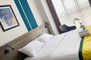 um quarto com uma cama com lençóis brancos e uma janela em Hotel Dhika Serenity Surabaya em Surabaya