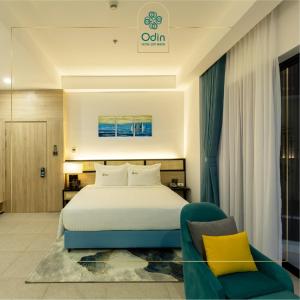 a hotel room with a bed and a chair at Odin Hotel Quy Nhon in Quy Nhon