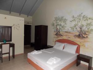 a bedroom with a bed and a painting on the wall at Hotel Theasis in Paralía Sergoúlas
