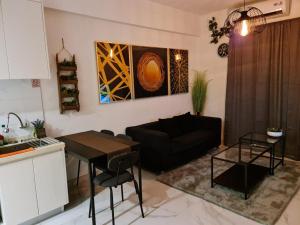 a living room with a black couch and a table at Sky House BSD 2 Bedrooms by Shinzhouz in Tjilandak