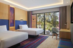 a hotel room with two beds and a desk at Aloft Langkawi Pantai Tengah in Pantai Cenang