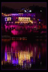 um edifício com luzes roxas na água à noite em Hotel Bharatpur Palace em Pushkar