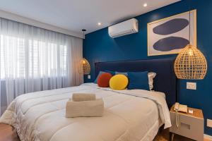 Cyclinn Berrini في ساو باولو: غرفة نوم زرقاء مع سرير كبير مع وسائد ملونة