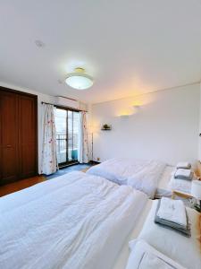 a bedroom with two white beds and a window at 大阪市東成区一軒家貸し切りファミリー向け小型車のみ無料駐車場可Private for families, small car free parking独栋可停小车 in Osaka