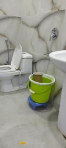 a bathroom with a toilet and a green bucket at Hotel golden gate dx in New Delhi