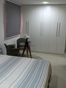 a bedroom with a bed and a table and chairs at Moderno apartamento perto da praia in Maceió
