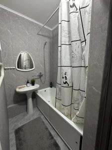 a bathroom with a tub and a sink and a shower curtain at 1 комнатная квартира, in Kokshetau