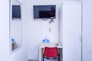 ジャカルタにあるHotel Global Syariahのデスク、赤い椅子、テレビが備わる客室です。