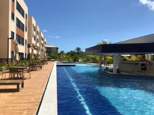 einen Pool in einem Resort mit Tischen und Stühlen in der Unterkunft Guarajuba, Camaçari, Bahia, 2 quartos com suíte, cobertura, terraço in Camassari