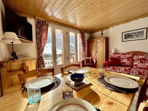 a dining room with a wooden table with chairs and a couch at Studio rénové, 4 couchages, proche pistes et commerces - FR-1-330F-231 in La Salle Les Alpes +6 photos