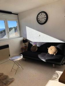 a living room with a black couch and a clock at Résidence Les Glovettes - Studio pour 4 Personnes 404 in Villard-de-Lans