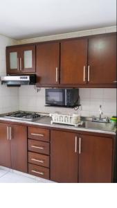 eine Küche mit Holzschränken, einer Mikrowelle und einer Spüle in der Unterkunft 3 Bedroom, 2 bathroom Located Cabecera del LLano. in Bucaramanga