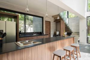 a kitchen with a counter and some stools at Twelve O'Clock - Luxury Villas in Tulum