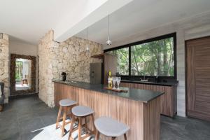 a kitchen with a counter with stools and a window at Twelve O'Clock - Luxury Villas in Tulum