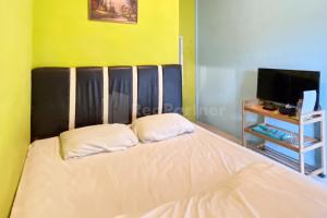 Cette chambre comprend un lit avec deux oreillers et une télévision. dans l'établissement Penginapan Gindo Sidebuk Debuk Berastagi RedPartner, à Berastagi