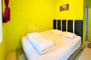 - un lit dans une chambre jaune avec 2 oreillers dans l'établissement Penginapan Gindo Sidebuk Debuk Berastagi RedPartner, à Berastagi