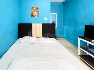 1 dormitorio con 1 cama grande y pared azul en Penginapan Gindo Sidebuk Debuk Berastagi RedPartner, en Berastagi