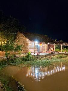 Una cabaña de noche con luces encendidas. en LA'S FARMSTAY en Tây Ninh