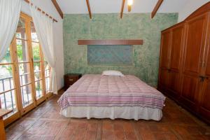 a bedroom with a bed and green walls and windows at Degustar Restaurante Hotel Boutique in Tinquipaya