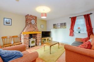 a living room with a brick fireplace with a couch and a tv at Tarporley Holiday Cottage in Tarporley