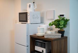 a microwave sitting on top of a wooden stand next to a refrigerator at REPURE OMORI RESIDENCE in Tokyo