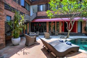 a courtyard with a pool and chairs and a building at Melo Suites Hotel in Seminyak