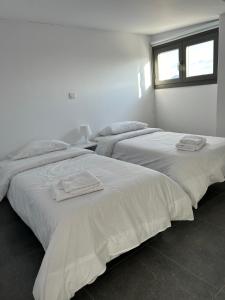 twee bedden in een witte kamer met handdoeken erop bij Arxaia skala in Kyperounda