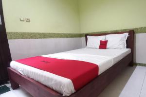 a bedroom with a large bed with a red blanket at RedDoorz Syariah near Bypass Krian in Gabung