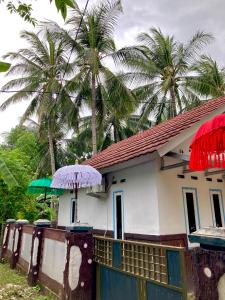 une petite maison avec un parasol et des palmiers dans l'établissement Batubutir homestay, à Midang